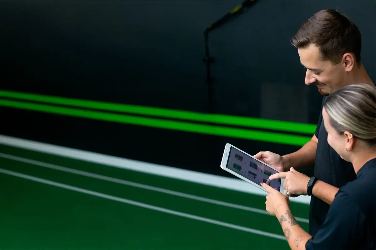 Dupla de profissionais da DoctorFit acompanhando a evolução do aluno pelo sistema de treino no tablet